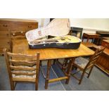 A mid 20th Century oak gate leg dining table; a set of four ladder back oak dining chairs,