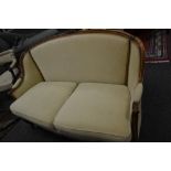 A Victorian walnut salon sofa shaped and carved throughout and upholstered in cream