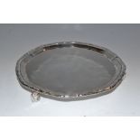 A silver shaped circular card waiter , ribbon tied reeded border,