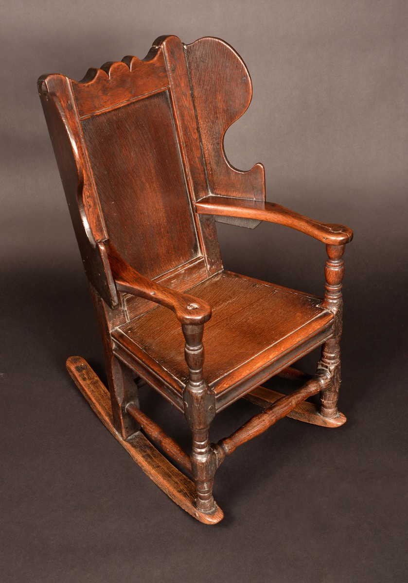 An 18th century child's wingback rocking chair, panelled back, shaped wing panels, turned legs, c.