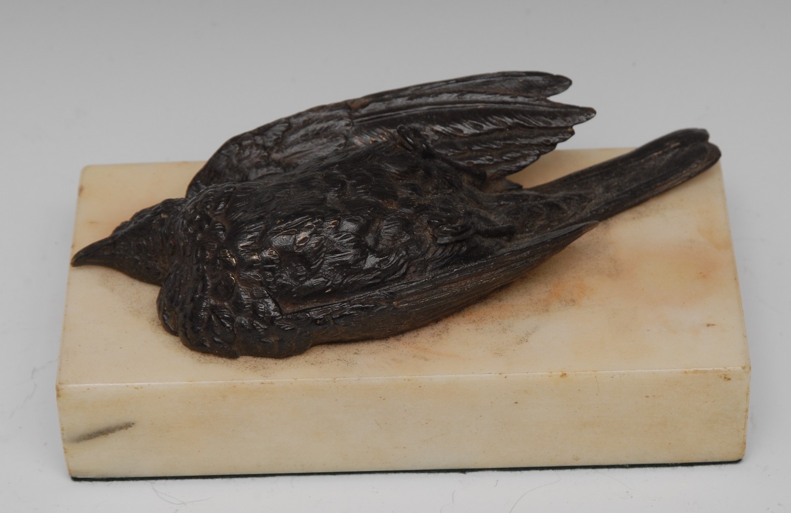 A 19th century desk weight, cast with a bronze dead song bird, on rectangular white marble base,