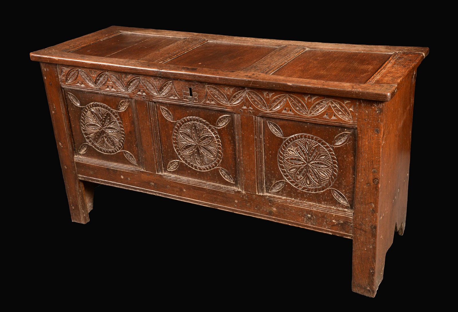 An 18th century oak blanket box, three panel top carved with initials E.B, stile feet, c.1720.