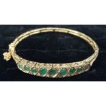 An Edwardian emerald and diamond hinge bangle, central row of nine graduated emeralds,