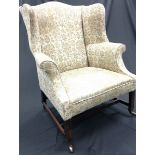 A George III mahogany wing back armchair, stuffed-over upholstery, chamfered square legs,