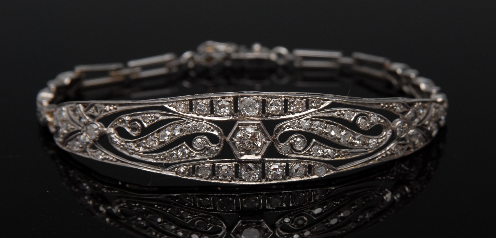 An Art Deco diamond bangle, arched open crest,