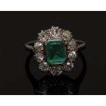A emerald and diamond cluster ring, central octagonal step cut emerald, approx 0.