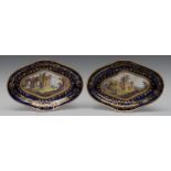 A pair of Coalport shaped circular dishes, painted with castle and ruins, deep cobalt blue border,