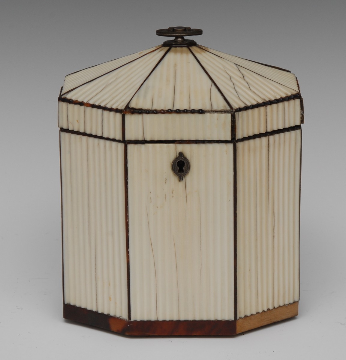 A George III ivory octagonal tea caddy, hinged cover with silvered axehead handle, fluted veneers,