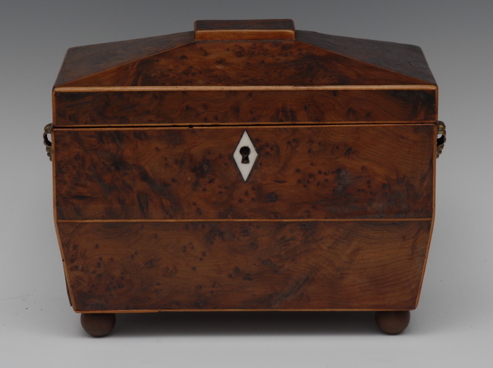 A George III yew sarcophagus tea caddy, hinged cover enclosing a pair of lidded compartments,