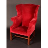 A George III style mahogany wingback armchair, stuffed-over scarlet plush upholstery, square legs,