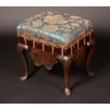 An early 18th century oak rectangular stool, stuffed-over seat, deep shaped apron, cabriole legs,