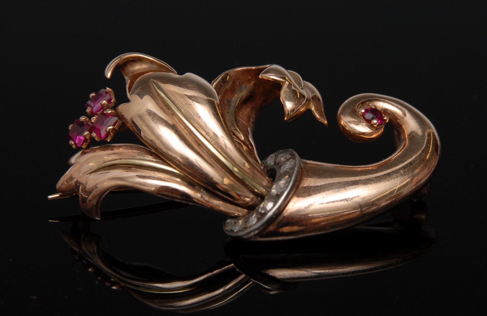 A ruby and diamond cornucopia brooch, arching cornucopia body,