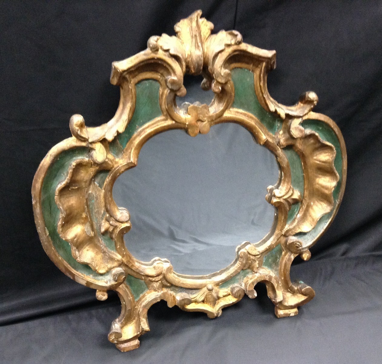 An 18th century carved, parcel-gilt and painted cartouche shaped looking glass,