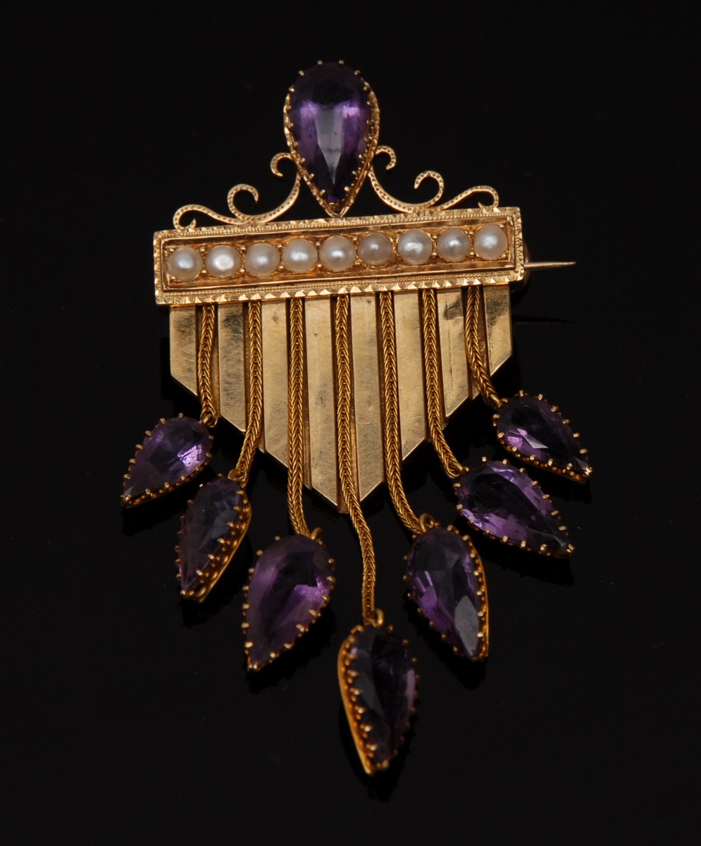 An unusual amethyst and seed pearl brooch, scrolling topped central panel,