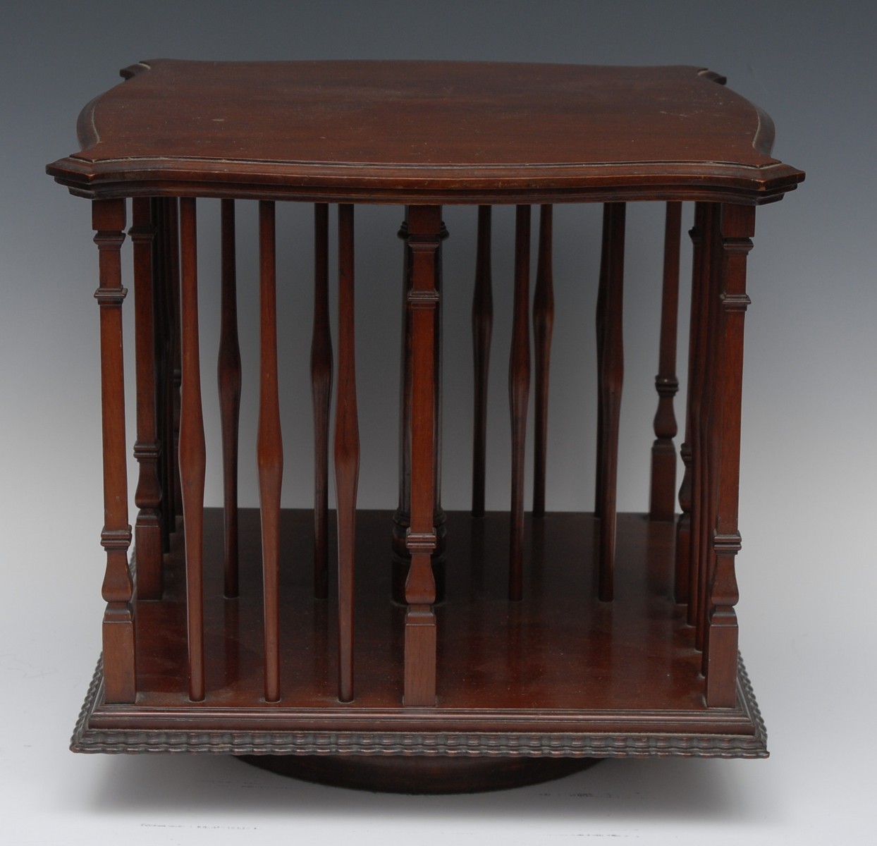 An Edwardian mahogany serpentine table top revolving bookcase, moulded and fluted borders,