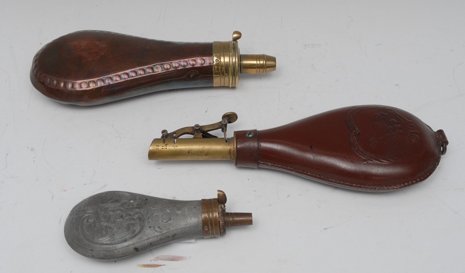 A 19th century copper and brass powder flask, beaded border, stamped Sykes, 20cm long; another,