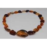 An amber necklace, composed of twenty three graduated irregular rough and polished angular beads,