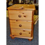 A contemporary pine three drawer bed side cabinet