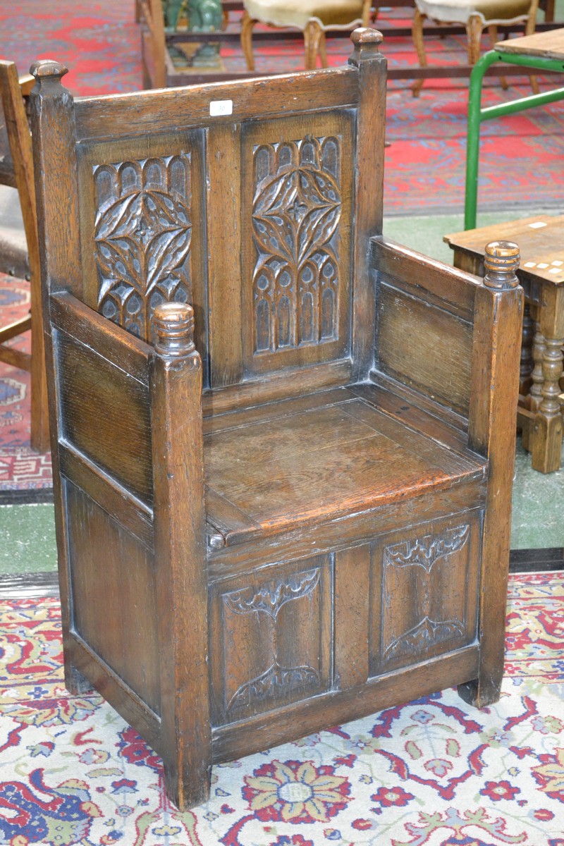 A monastic style hall settle, two carved panel back, hinged seat enclosing storage,