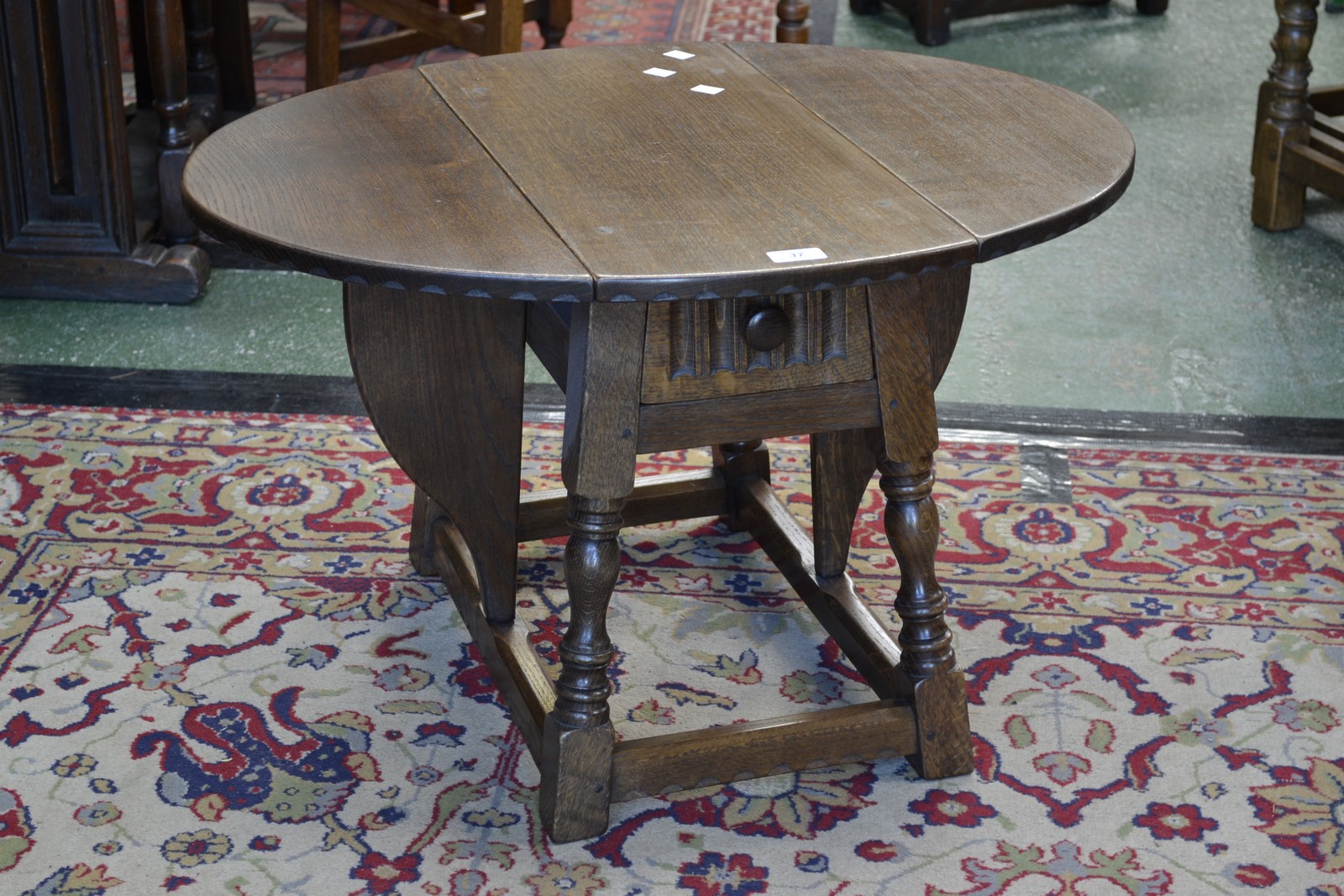 An oak Rupert Griffith drop leaf occasional table, oval top, turned supports.