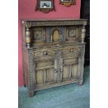 A monastic style court cupboard, blind fretworked frieze, two carved door cupboard to top,
