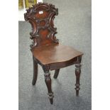 A flame mahogany hall chair, the back shaped and carved with C scrolls and foliage,