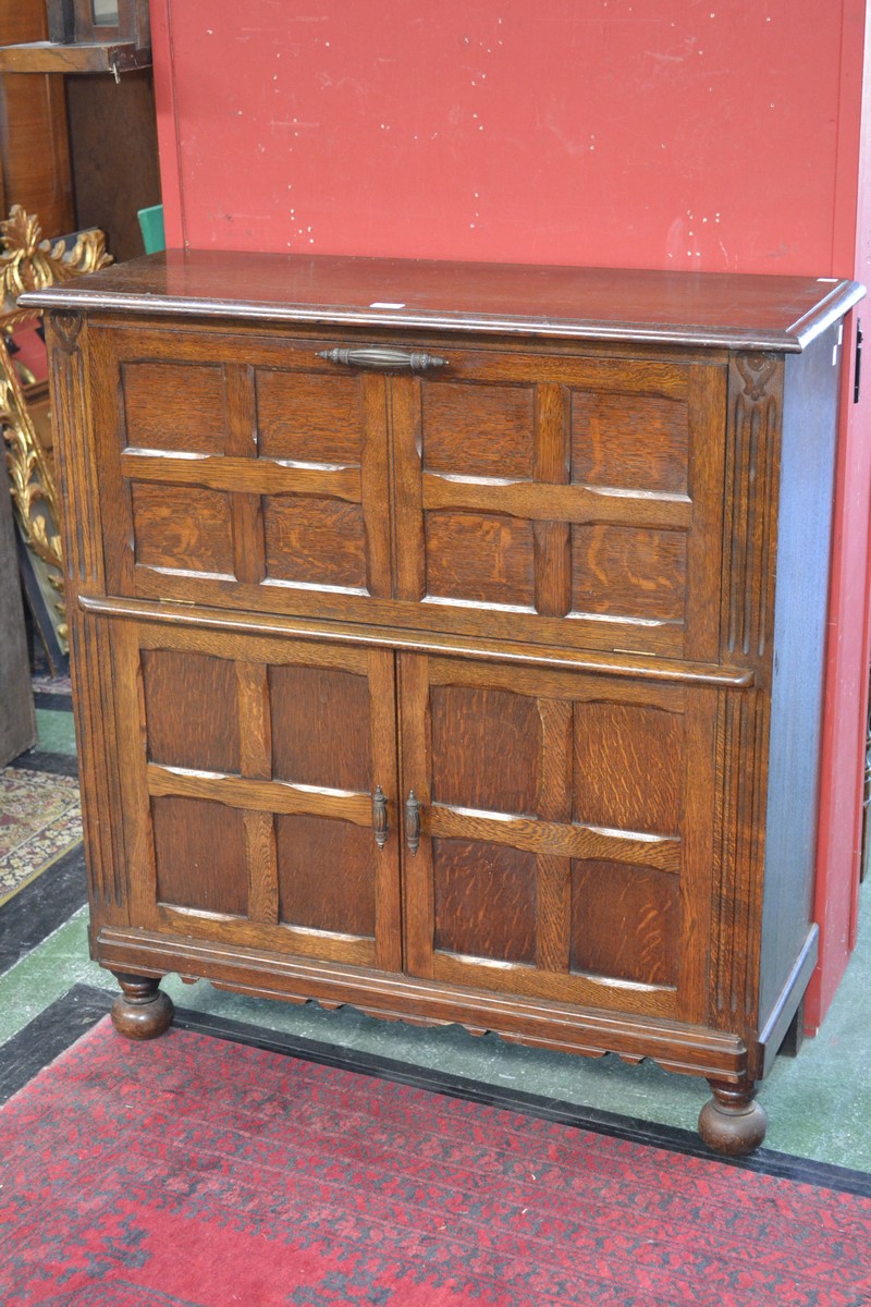 A 1940`s oak drinks cabinet, a fall front door to top, a pair of panelled cupboard doors to base.