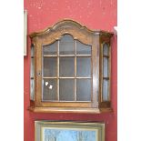 Two contemporary wall mounted display cabinets, arched top, astragal glazed door, canted angles.