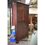 A George III mahogany floor standing corner cabinet of large proportions, outswept cornice,