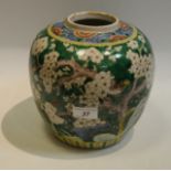 A Chinese ginger jar, painted with white blossom trees, birds of prey and rockery on a green ground,