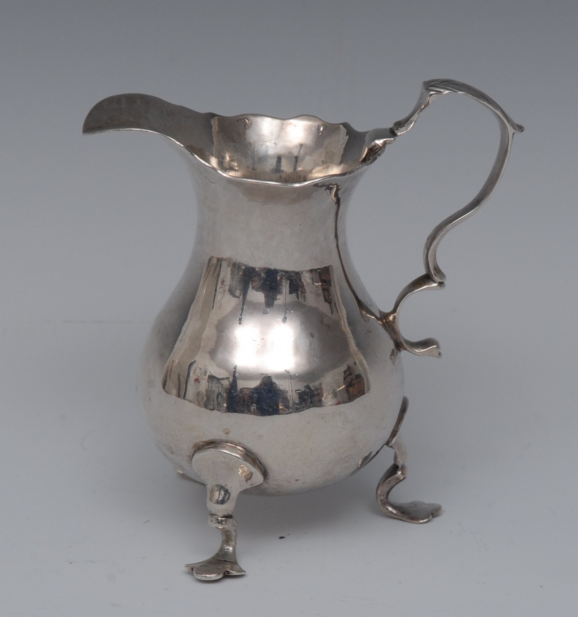 A George II silver cream jug, wavy rim, acanthus capped double scroll handle, shaped pad feet,