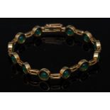 An emerald and gold coloured metal bracelet, composed of twelve emerald beaded circular panels,