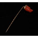 A carved coral Dogs Head stick pin, carved as a Pointer, spiralled gold shaft, 74mm long,
