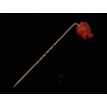 A carved coral dog's head stick pin, carved as a stylized French Bulldog, spiralled gold shaft,