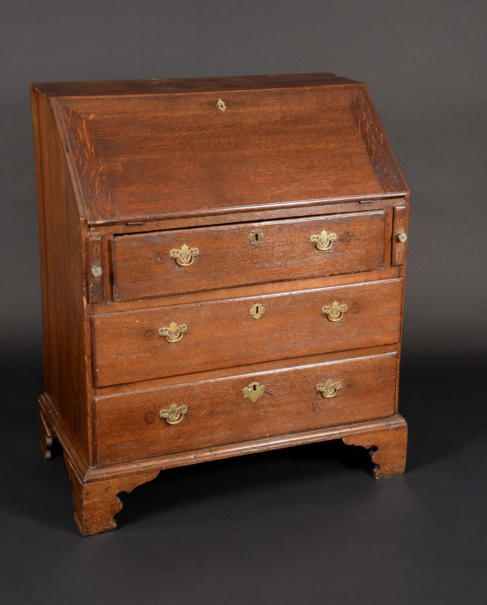 A George III oak bureau, the fall front enclosing a fitted interior of drawers and pigeon holes,