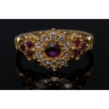 A ruby and diamond cluster ring, central round pinky red ruby,