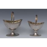 A graduated pair of George III Neo-Classical silver boat shaped swing-handled pedestal sugar