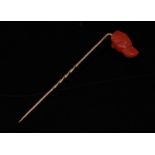 A carved coral dog's head stick pin, carved as a Labrador, spiralled gold shaft, 75mm long,
