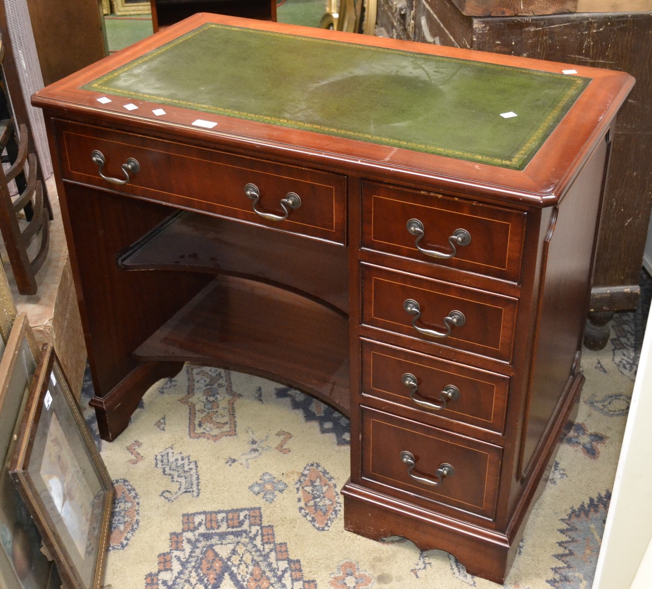 A reproduction mahogany desk, leather green top, swing handles,