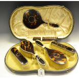 A George V silver, tortoiseshell and pique dressing table set, comprising a hand mirror,