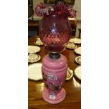 A Victorian oil lamp, cranberry glass shade, painted with leaves and foliage, c.