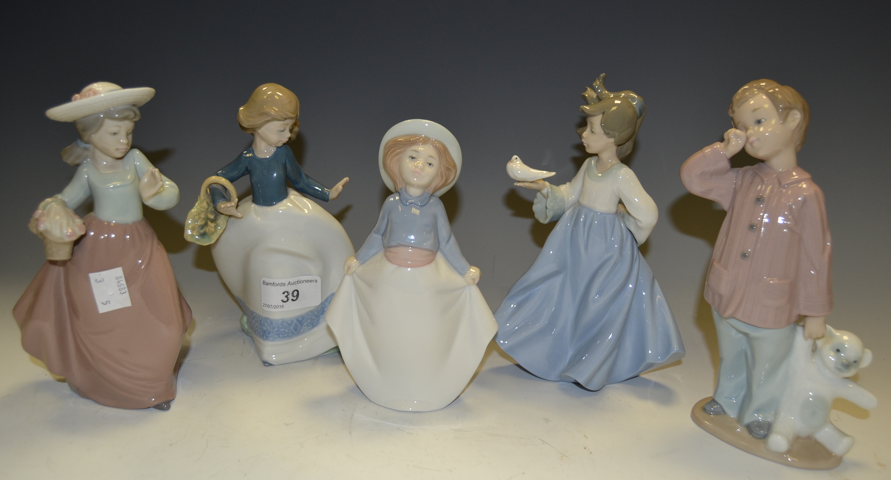 A Nao figure of a boy with a bear; others of young girls, various poses.