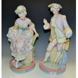 A pair of French bisque figures, of Cinderella and Prince Charming, he with a shoe, in pastel tones,