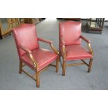 A pair of mahogany and red leather boardroom elbow chairs in the 19th century style