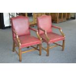 A pair of mahogany and red leather boardroom elbow chairs in the 19th century style