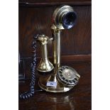 A reproduction brass dial-up candlestick telephone