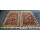 A pair of throw rugs, geometric designs in red, taupe, mustard and indigo on a beige ground.