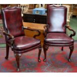 A pair of 20th Century mahogany ox blood leather boardroom elbow chairs, cabriole legs.