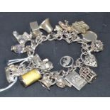 A sterling silver gate link bracelet, with a selection of charms, including, church, piano,