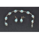 A silver bracelet and earrings set with blue stones